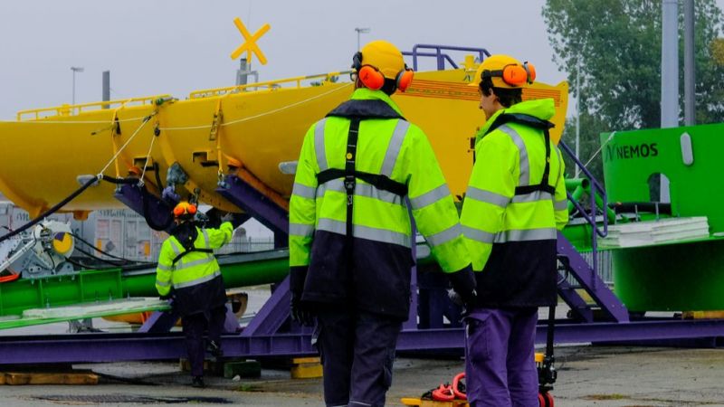 Die Ingenieurinnen und Ingenieure bereiten die Versuchsanlage des NEMOS-Wellenkraftwerks im Hafen von Ostende auf die Versuche vor.
