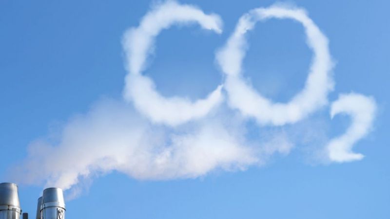 Industrieschornstein, aus dem eine Wolke entströmt, die das Wort CO2 bildet
