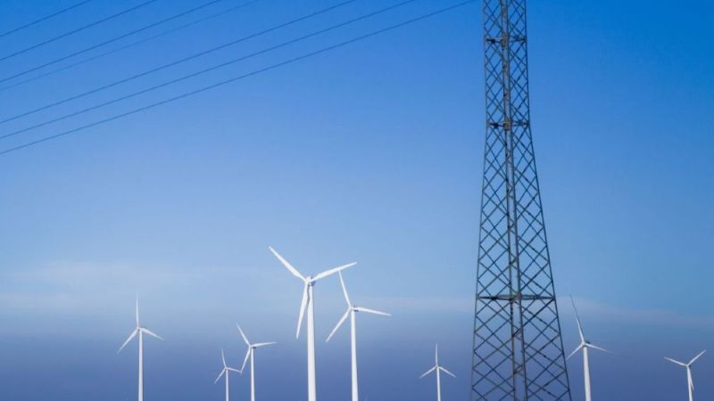 Windenergieanlagen und Stromnetz vor blauem Himmel