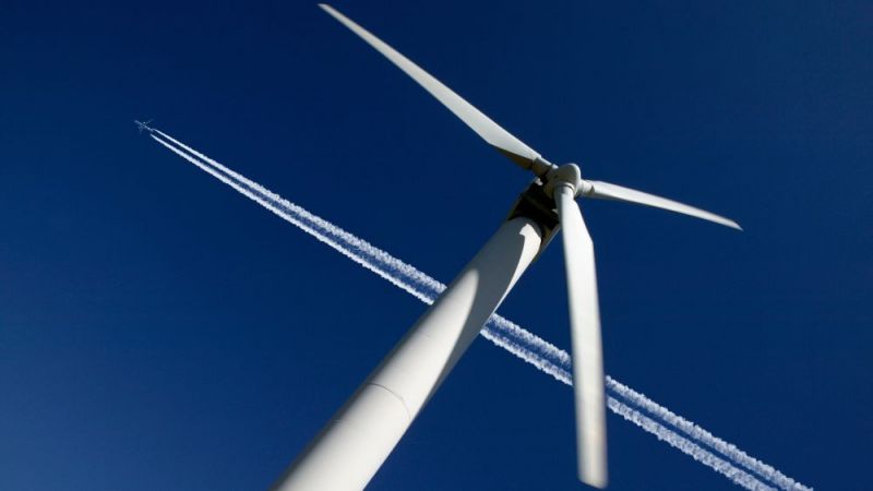 Aircraft flying over a wind turbine.