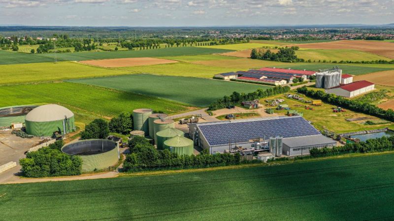 Das Foto zeigt eine Biogasanlage sowie eine Photovoltaikanlage auf einem landwirtschaftlich genutzten Gebäude.