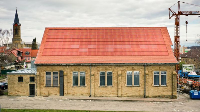Das Foto zeigt die ziegelrote Photovoltaikanlage auf dem Dach einer Turnhalle in Eppingen, die im Rahmen des Forschungsprojekts PVHide entwickelt wurde.