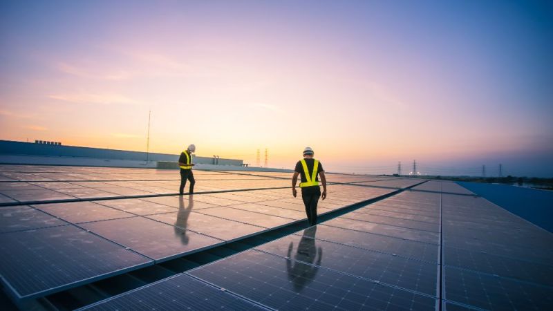 Symbolfoto: Ingenieure überprüfen am Morgen installierte Solarzellen auf dem Dach einer Fabrik.