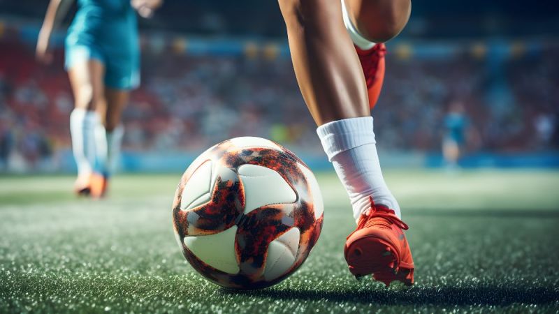 Symbolfoto: Eine Fußballspielerin läuft mit dem Ball am Fuß über den Stadionrasen.
