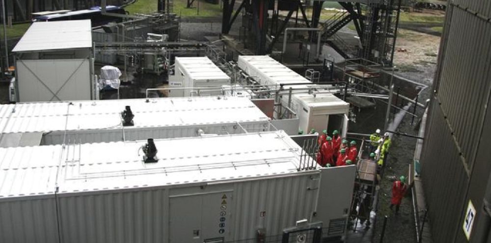Fünf hellgraue Container auf dem Gelände des RWE-Kohlekraftwerks Niederaußem.