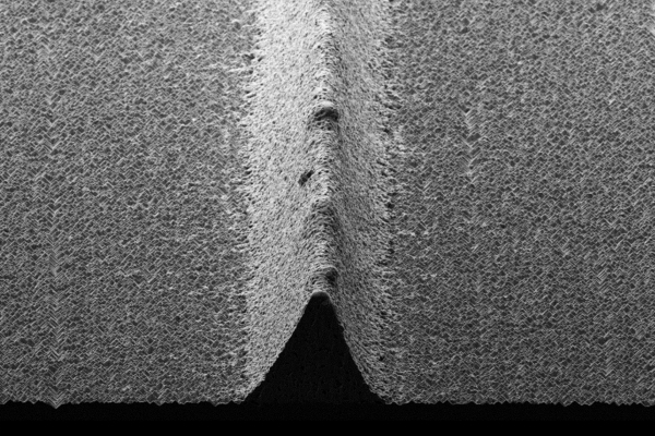 Rasterelektronenmikroskop-Aufnahme, ein dreieckiger unterbrechungsfreier Solarzellenkontakt mit glatten Ausßenkanten ist im Querschnitt zu erkennen. Dieser befindet sich auf einer Solarzelle.