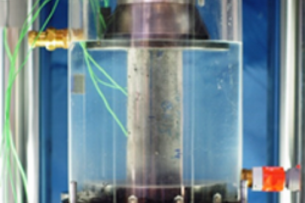 The photo shows the set-up of a fatigue test on a concrete cylinder under water.
